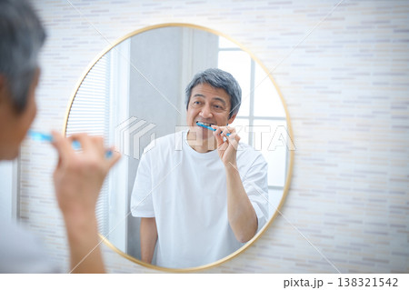 鏡を見ながら歯磨きをする60代の男性 138321542