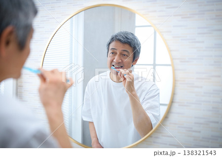 鏡を見ながら歯磨きをする60代の男性 鏡を見ながら歯磨きをする60代の男性 138321543
