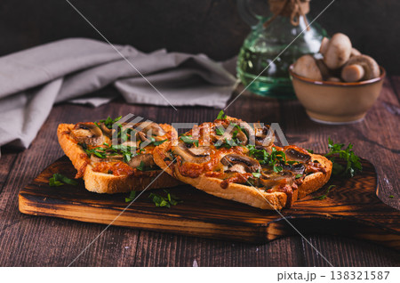 Delicious baked sandwiches with cheese, mushrooms and herbs on a board on the table Delicious baked sandwiches with cheese, mushrooms and herbs on a board on the table 138321587