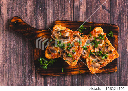 Close up of delicious baked sandwiches with cheese, mushrooms and herbs on a board top view 138321592