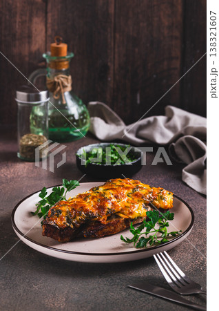 Pork loin baked with cheese, tomatoes and mushrooms on a plate on the table vertical view Pork loin baked with cheese, tomatoes and mushrooms on a plate on the table vertical view 138321607