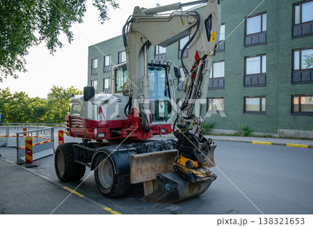Urban construction excavator parked on street with digging bucket heavy machinery road work infrastructure concept Urban construction excavator parked on street with digging bucket heavy machinery road work infrastructure concept 138321653