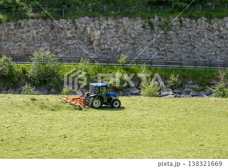 Blue tractor mowing grass field with agricultural machinery farming landscape rural work concept 138321669