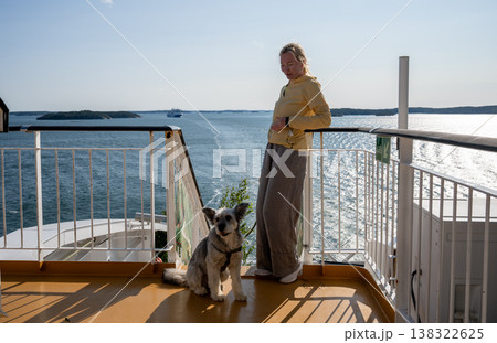 Woman with dog on ferry deck enjoying Baltic sea view during sunny travel journey Woman with dog on ferry deck enjoying Baltic sea view during sunny travel journey 138322625