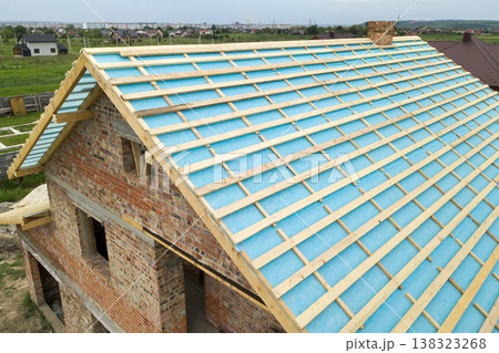Aerial view of a brick house with wooden roof frame under construction. Aerial view of a brick house with wooden roof frame under construction. 138323268