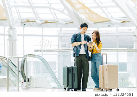 旅先のショッピングモールでスマホを見るカップル　「撮影協力：関西国際空港（KIX）」 138324581