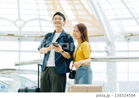 旅先のショッピングモールでスマホを見るカップル　「撮影協力：関西国際空港（KIX）」 138324584