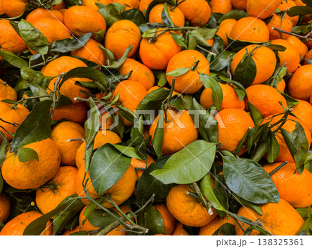 Vibrant background pattern of fresh organic mandarins with green leaves at market Vibrant background pattern of fresh organic mandarins with green leaves at market 138325361
