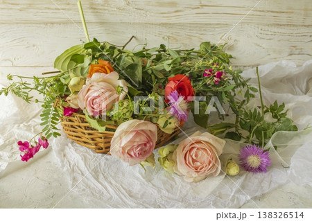 Fresh flower arrangement with roses and wildflowers in a wicker basket. Rustic flower arrangement with flowers from the garden. Fresh flower arrangement with roses and wildflowers in a wicker basket. Rustic flower arrangement with flowers from the garden. 138326514