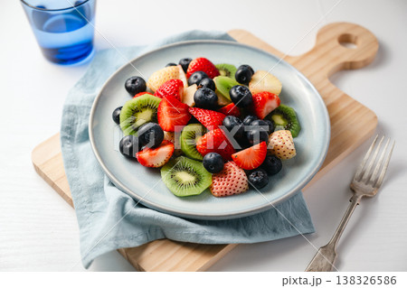 Fresh fruit salad in a plate, kiwi slices, strawberries and blueberries. Healthy food, sweet dessert, top view 138326586