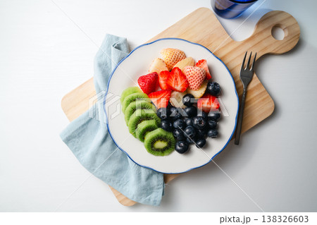 Fresh fruit salad in a plate, kiwi slices, strawberries and blueberries. Healthy food, sweet dessert, top view Fresh fruit salad in a plate, kiwi slices, strawberries and blueberries. Healthy food, sweet dessert, top view 138326603