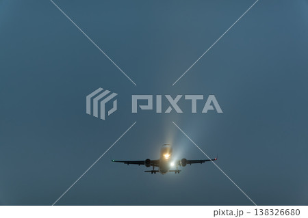 Airplane approaching for landing with landing lights illuminated against a dark, cloudy sky during twilight hours, showcasing aviation and transportation themes Airplane approaching for landing with landing lights illuminated against a dark, cloudy sky during twilight hours, showcasing aviation and transportation themes 138326680