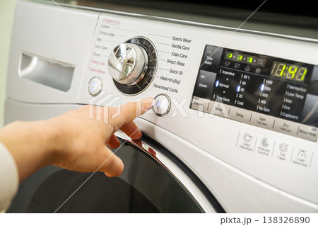Washing machine. Pressing start button on modern washing machine display. Daily chores, close-up shot Washing machine. Pressing start button on modern washing machine display. Daily chores, close-up shot 138326890