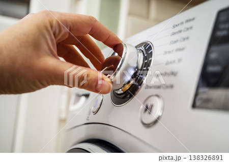 Smart home appliances. Adjusting washing machine setting. Hand turning the dial of a modern washing machine. Daily chores 138326891