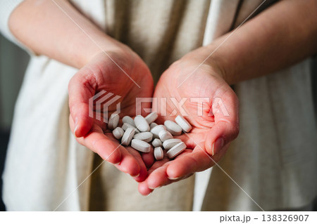 Woman's hands holding a pile of pills and capsules. Prescription medication, treatment sickness concept Woman's hands holding a pile of pills and capsules. Prescription medication, treatment sickness concept 138326907