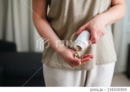 Woman pouring a pile of pills, capsules from a bottle in hand. Prescription medication, treatment sickness concept Woman pouring a pile of pills, capsules from a bottle in hand. Prescription medication, treatment sickness concept 138326909
