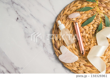 Rose quartz gua sha tool and face massage roller on wooden tray, beauty abstract photo. Top view 138326961