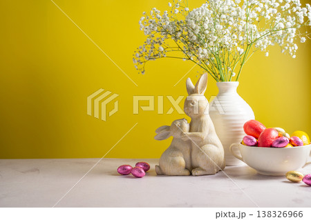 Easter chocolate colourful eggs in a bowl, cute bunnies and gypsophila flowers in a vase. Spring holiday background. Easter chocolate colourful eggs in a bowl, cute bunnies and gypsophila flowers in a vase. Spring holiday background. 138326966