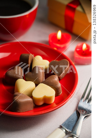 Valentine's Day chocolate candies in red plate served with a cup of coffee and candles 138326969