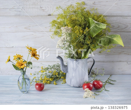 Summer still life with fresh dill, rudbeckia and tomatoes in an old jug. Rustic still life with yellow flowers and greenery on a wooden table. 138326975
