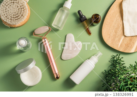 Rose quartz gua sha tool and face massage roller on green background, beauty abstract photo. Top view Rose quartz gua sha tool and face massage roller on green background, beauty abstract photo. Top view 138326991
