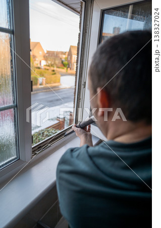 Spring home cleaning. Man vacuums plastic window frame. 138327024