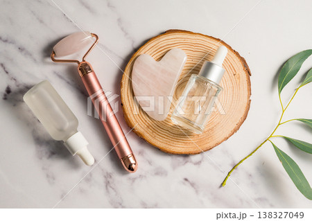 Rose quartz gua sha tool and face massage roller on wooden tray, beauty abstract photo. Top view Rose quartz gua sha tool and face massage roller on wooden tray, beauty abstract photo. Top view 138327049