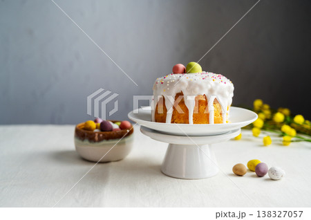 Easter festive cake with icing, sprinkles and eggs candy. White eggs and spring, yellow flower twigs. Easter festive cake with icing, sprinkles and eggs candy. White eggs and spring, yellow flower twigs. 138327057