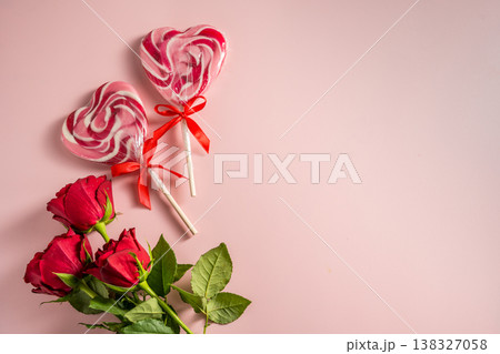 Valentine's Day background. Red roses and heart shaped lolly candy over pink background. Abstract flat lay. Celebrate, festive greeting card. 138327058