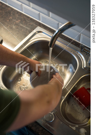 A man washing dishes in the kitchen, home chores, daily routine A man washing dishes in the kitchen, home chores, daily routine 138327059