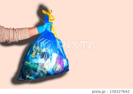 Hand holding full garbage bag on beige background isolated. High quality image 138327642