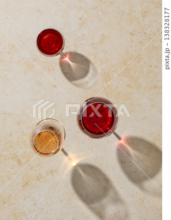 Three wine glasses on light beige background with sunlight, top view 138328177