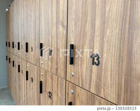 Wooden locker row with numbered doors and handles in modern changing room interior. Storage system organization, personal item security, gym facility infrastructure and user access concept Wooden locker row with numbered doors and handles in modern changing room interior. Storage system organization, personal item security, gym facility infrastructure and user access concept 138328513
