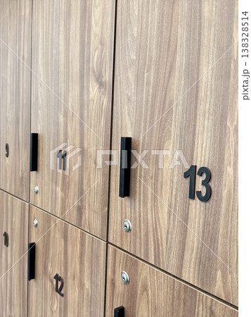 Wooden locker row with numbered doors and handles in modern changing room interior. Storage system organization, personal item security, gym facility infrastructure and user access concept Wooden locker row with numbered doors and handles in modern changing room interior. Storage system organization, personal item security, gym facility infrastructure and user access concept 138328514