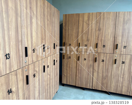 Wooden locker wall with numbered doors in modern changing room interior at fitness facility. Personal storage organization, user access control, locker allocation and everyday gym infrastructure 138328519