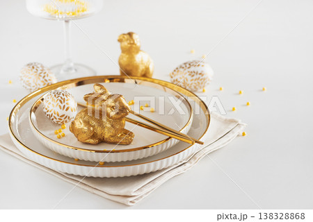 Easter Table Setting with Plates and Golden Decor on White Table 138328868