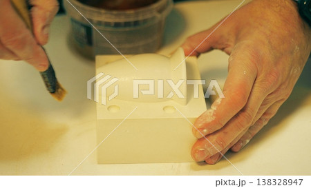 Close up of potter applying mold release with a brush to a plaster mold before casting the second mold part in a ceramics workshop. Step of plaster mold making process used for slip casting pottery 138328947