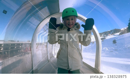 Little Girl In Helmet Riding Covered Magic Carpet Lift At Ski Resort in Chamrousse, French Alps 138328975