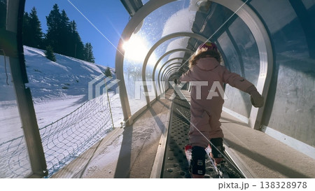 A small child riding a covered magic carpet lift on skis at a ski resort in the French Alps 138328978