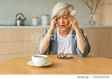 Headache pain. Unhappy middle aged senior woman suffering from headache sick rubbing temples at home. Mature old senior grandmother touching temples experiencing stress Woman feeling pain hurt in head Headache pain. Unhappy middle aged senior woman suffering from headache sick rubbing temples at home. Mature old senior grandmother touching temples experiencing stress Woman feeling pain hurt in head 138329156