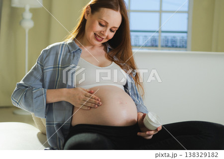 Pregnancy motherhood. Pregnant woman applying cream lotion on big belly takes care of her skin. Cosmetic product for prevention stretch mark. Girl enjoying pregnancy at home. Maternity health concept Pregnancy motherhood. Pregnant woman applying cream lotion on big belly takes care of her skin. Cosmetic product for prevention stretch mark. Girl enjoying pregnancy at home. Maternity health concept 138329182