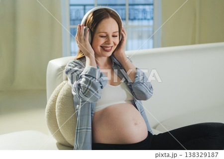 Pregnancy motherhood. Pregnant woman listening music for mother and unborn baby at home. Girl in headphones enjoying pregnancy listen music for relax healthy zen calm peace wellness, Maternity concept 138329187