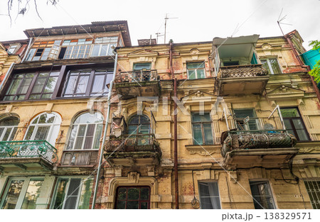 A part of the facade of an old early 20th century building among trees on the quiet green street of the small town in the South of Russia in summer 138329571