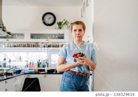 Mature woman with CGM glucose sensor preparing healthy meal at home kitchen. 138329616