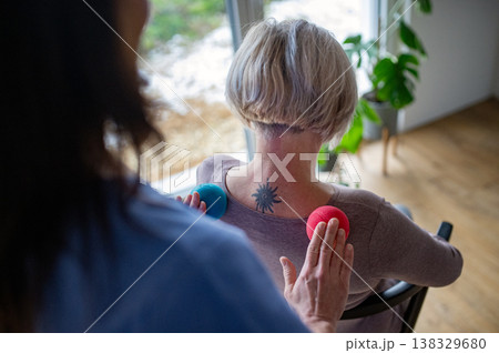 Physiotherapist helping senior woman with neck exercise, home therapy session. 138329680