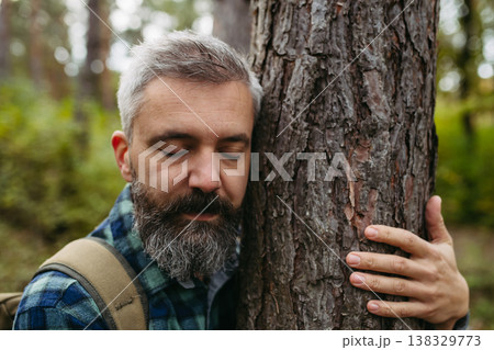 Handsome man standing in the middle of nature with closed eyes, hugging tree. Peaceful atmosphere of the forest, forestbathing. Handsome man standing in the middle of nature with closed eyes, hugging tree. Peaceful atmosphere of the forest, forestbathing. 138329773