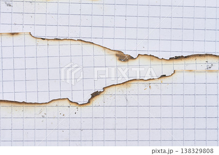 A sheet of white squared notebook paper with a badly burnt top edge and traces of dark soot, close up A sheet of white squared notebook paper with a badly burnt top edge and traces of dark soot, close up 138329808