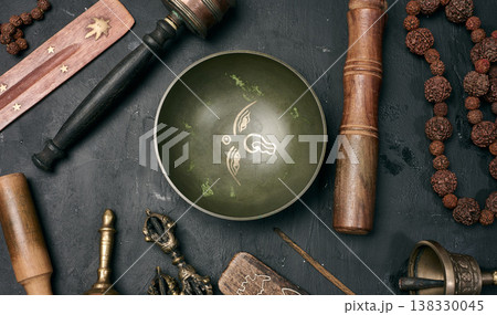 Tibetan singing bowl, wooden resonator, ritual vajras, bell, prayer wheel, rosary beads, and incense on a black background. Tibetan singing bowl, wooden resonator, ritual vajras, bell, prayer wheel, rosary beads, and incense on a black background. 138330045
