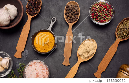 Various ground spices in wooden spoons, olive oil on dark table 138330052