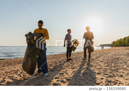 Earth day. Volunteers activists team collects garbage cleaning of beach coastal zone. Woman mans puts plastic trash in garbage bag on ocean shore. Environmental conservation coastal zone cleaning Earth day. Volunteers activists team collects garbage cleaning of beach coastal zone. Woman mans puts plastic trash in garbage bag on ocean shore. Environmental conservation coastal zone cleaning 138330080